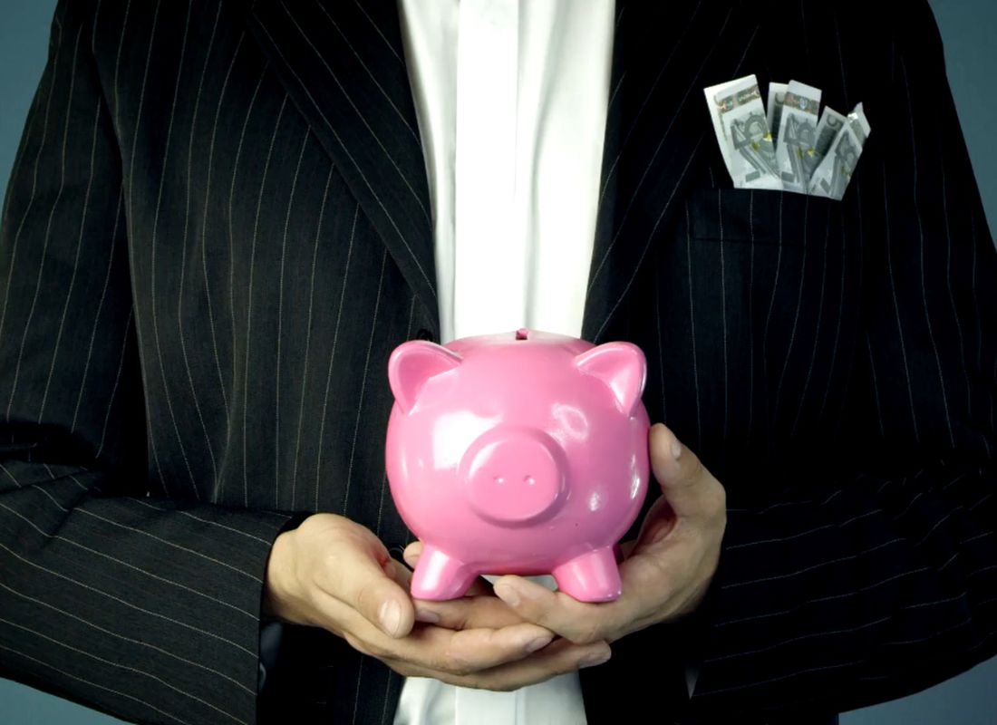 osoba drži kasicu u obliku praseta u rukama i sako na sebi u kom je novac